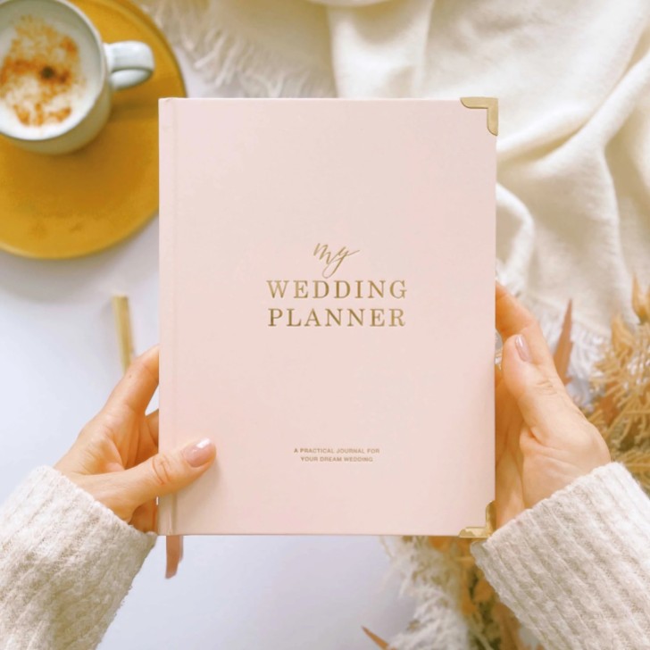 Libro de planificación de bodas de lujo en tonos rosa y dorado con bordes dorados